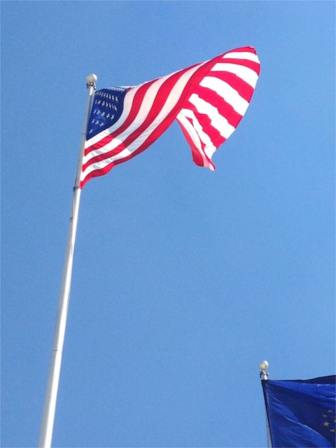 American flag blowing in the wind against a bright blue sky