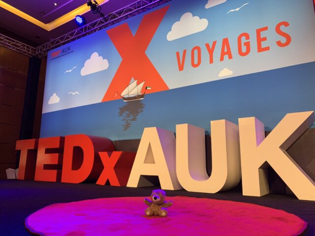 TEDx AUK stage with teddy bear in red circle
