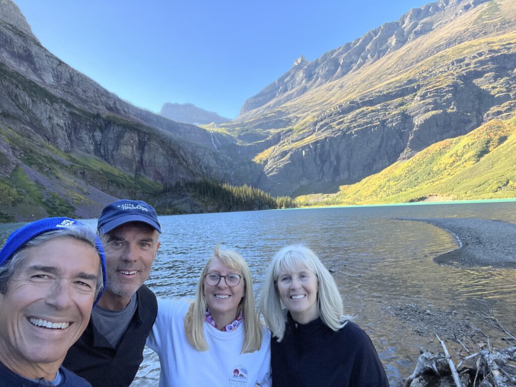 Four people next to a mountain lake