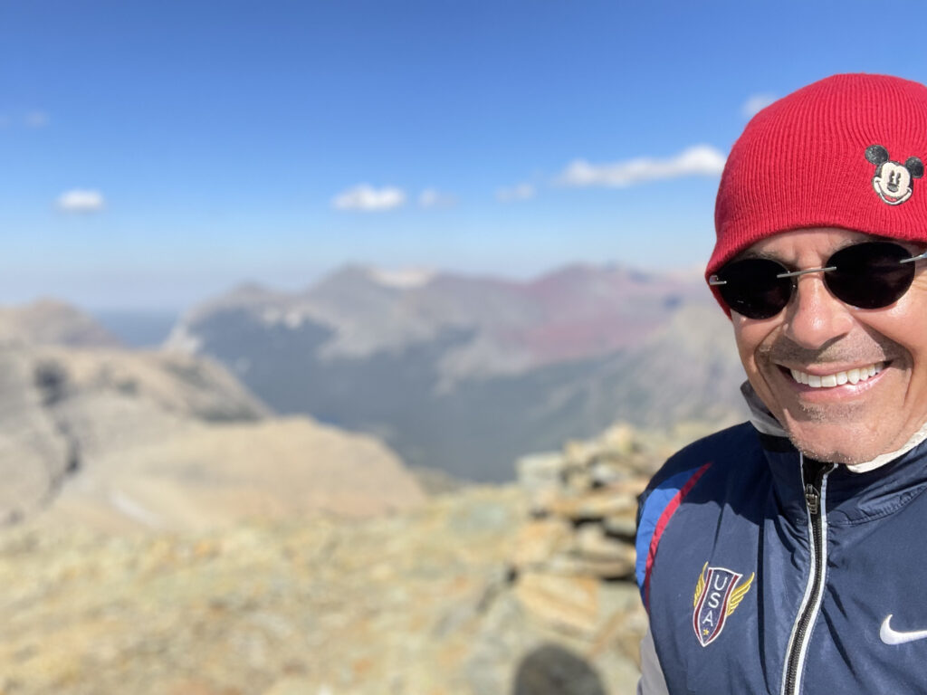 man wearing red hat and sunglasses on a mountain