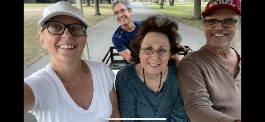 Four adults on a golf cart on the street