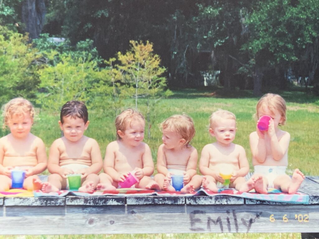 six toddlers in bathing suits on a dock