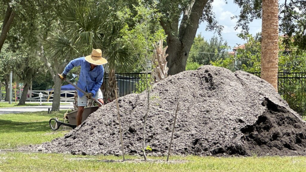 Person shoveling from a dirt pile