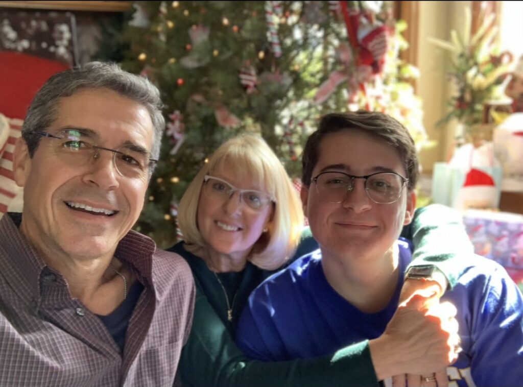 Family of three posing at a Christmas tree