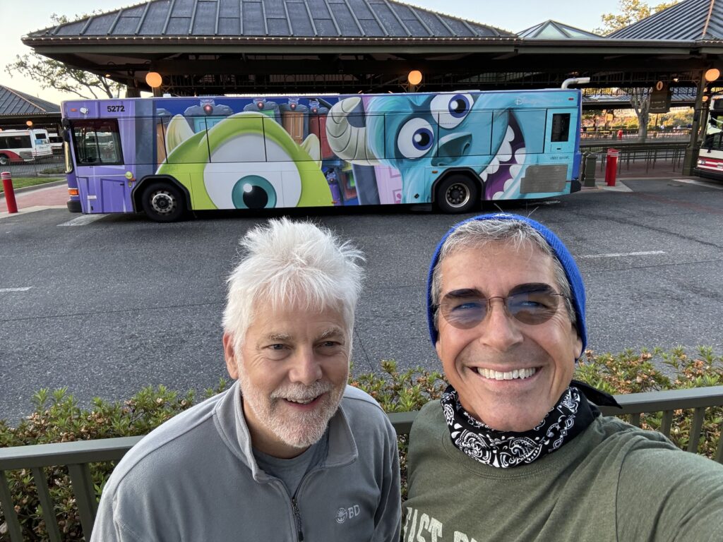 Two men posing by a Disney bus