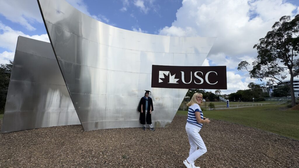Two adults in front of a large silver structure