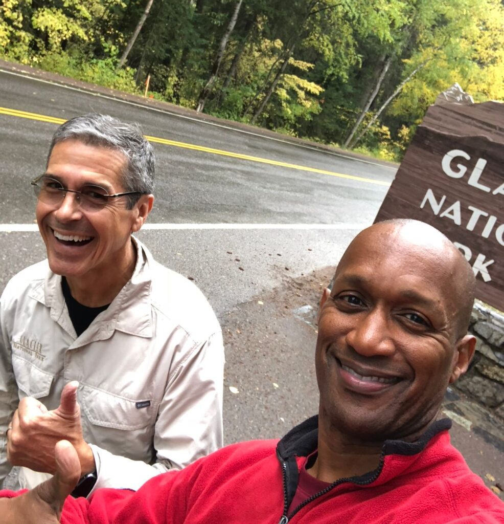 Two friends standing in front of a National Park sign